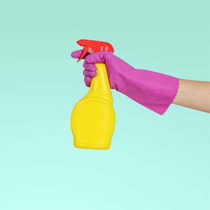 Hand covered in a purple glove holding yellow cleaning bottle